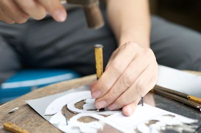 Midsection of person carving wood at workshop