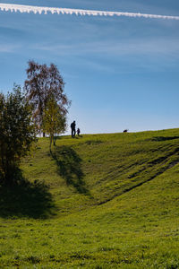 People walking on field against sky