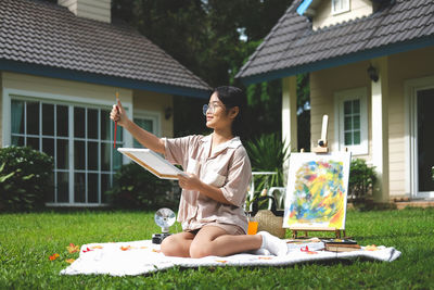 Full length of boy sitting in yard against house