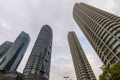 Low angle view of skyscrapers against cloudy sky