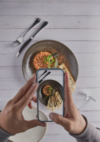 Hands with the phone close-up pictures of food tartar raw from tuna fillet with hashed avocado