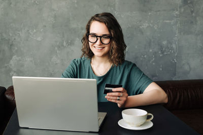 Portrait of young woman using laptop while sitting at home