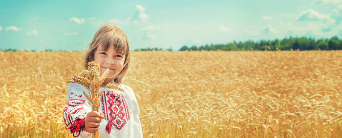 Cute girl with wheat standing at farm