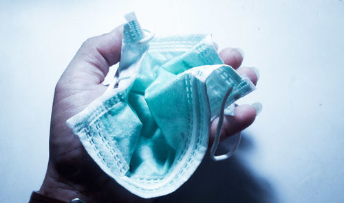 Close-up of human hand holding paper over white background