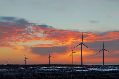 Wind turbines in sea against romantic sky