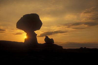 Silhouette woman standing on field against sky during sunset