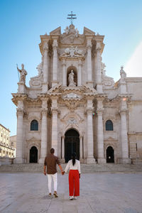 Rear view of people outside temple against building