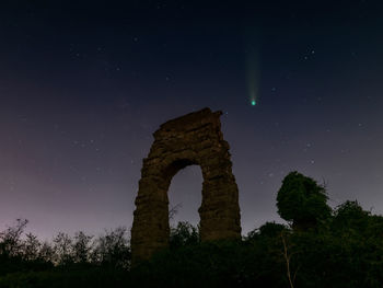 The comet neowise in the sky of rome, against the background of the ruins of an roman aqueduct.