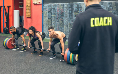 Mixed team lifting weights in the gym with their coach