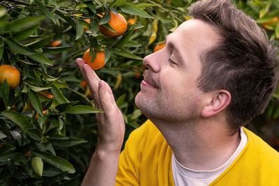 Side view of man holding orange fruit