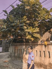 Woman standing by tree against building