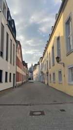 Empty road amidst buildings against sky