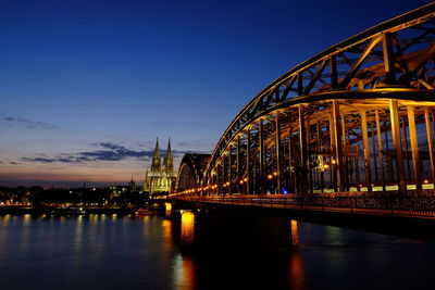 Illuminated bridge over river against sky at night