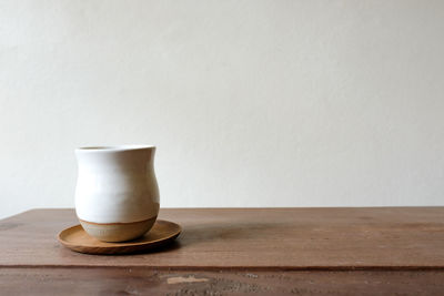 Close-up of coffee cup on table against wall