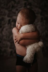 Boy embracing teddy bear at home