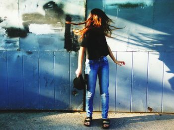 Woman tossing hair while standing against gate