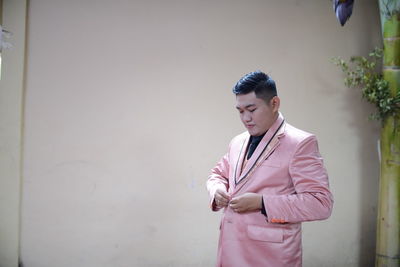 Young man looking at camera while standing against wall