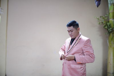 Young man looking at camera while standing against wall