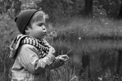 Side view of cute boy blowing dandelion