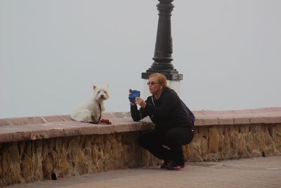 Young man using mobile phone against sky