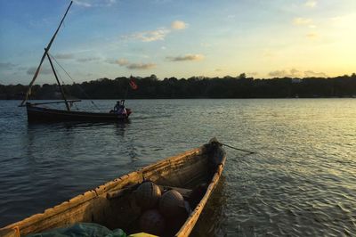 Sailboat in lake against sky during sunset