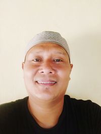 Close-up portrait of a smiling young man against wall