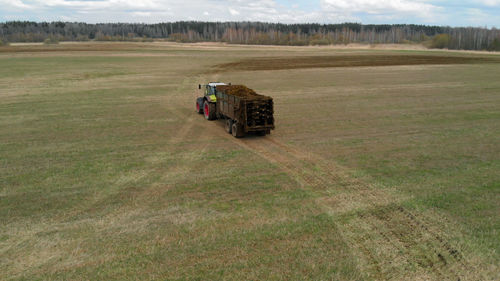 Tractor with a manure spreader rides through the field