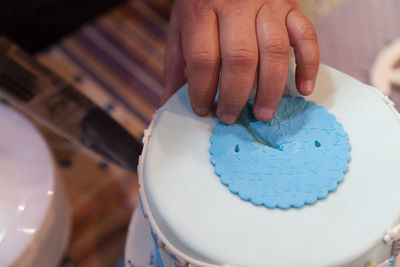 Cropped hand of person cutting cake from knife