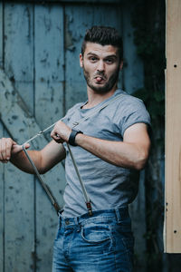 Portrait of young man standing against wall