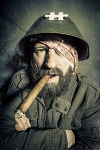 Portrait of bearded mature man wearing helmet smoking cigar
