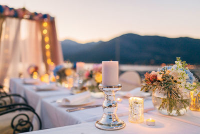 Close-up of illuminated place setting at restaurant against sky during sunset