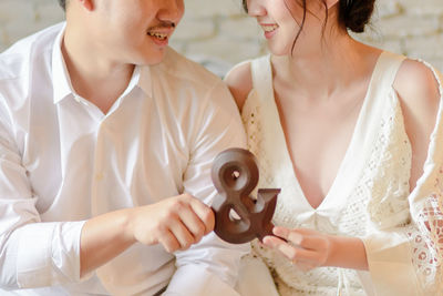 Midsection of couple holding wooden sign