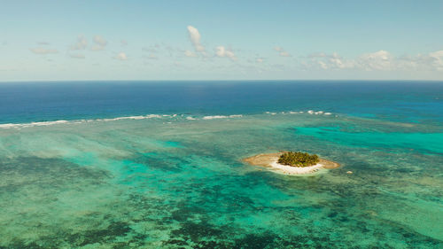 Sandy beach with tourists on tropical island with palm trees and turquoise water. guyam island