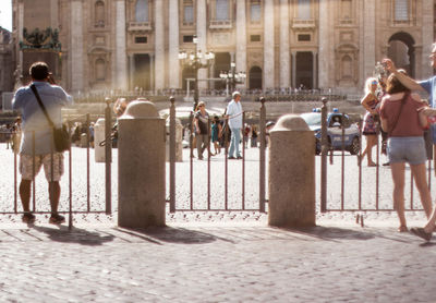 Rear view of people standing in front of historical building