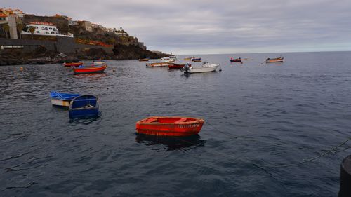 View of wooden and fishing boats in sea against sky off the coast of madeira