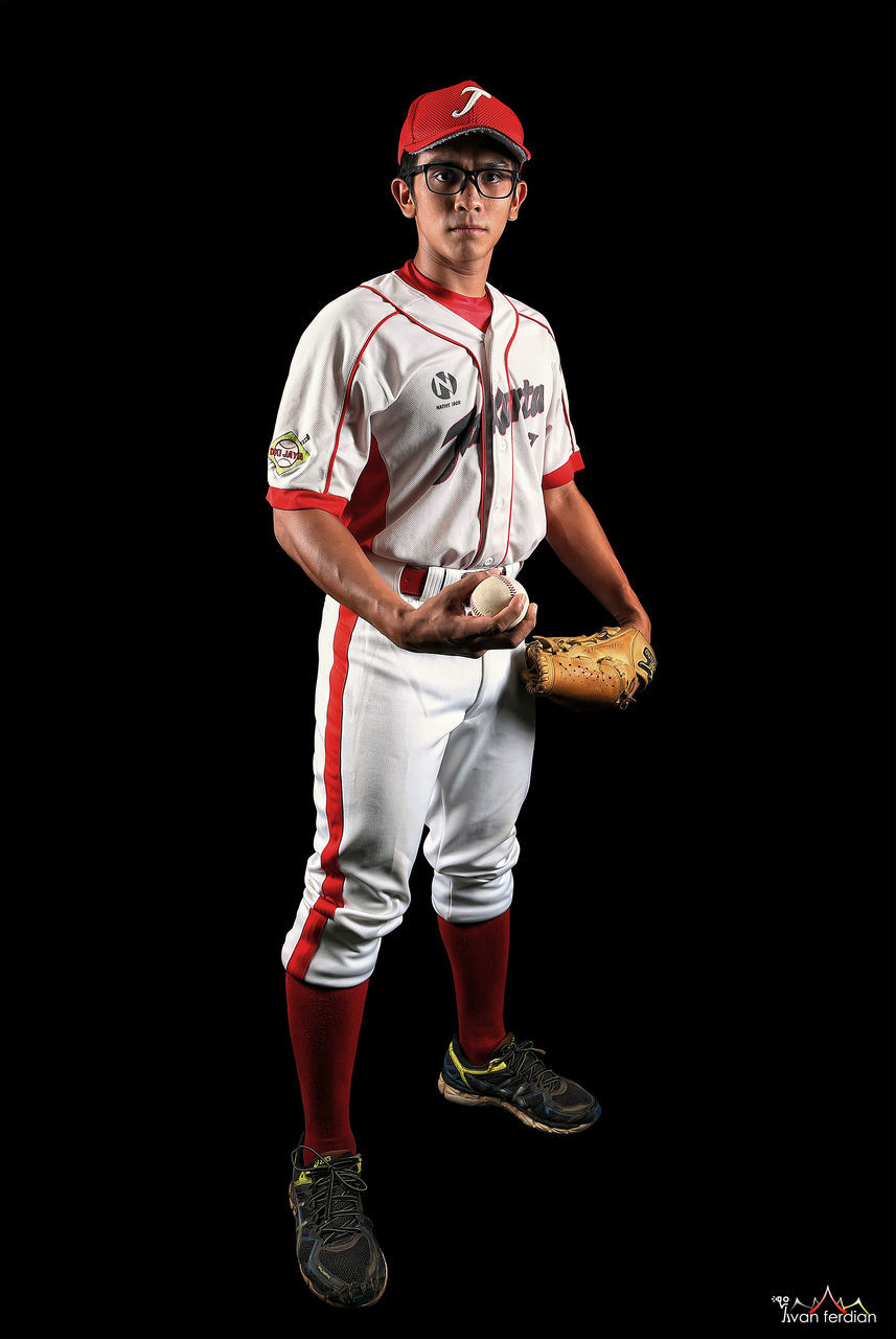 YOUNG MAN STANDING AGAINST BLACK BACKGROUND