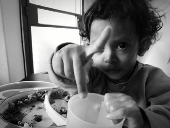 Portrait of cute toddler gesturing while holding glass at home