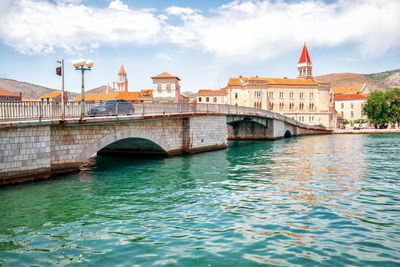 Arch bridge over river against buildings in city