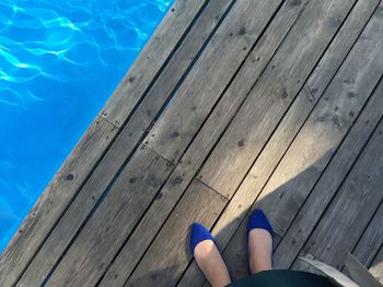 Low section of woman standing on boardwalk by pool