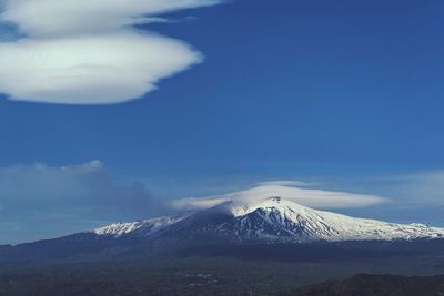 Scenic view of snow covered mountains against blue sky