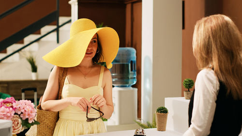 Rear view of woman wearing hat standing at home