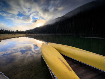 A pair of yellow canoes rest on lake on a beautiful october morning