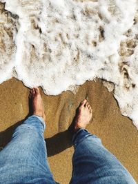 Low section of man standing on beach