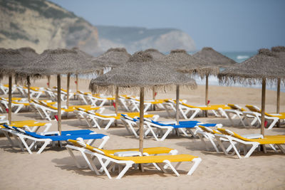 Sun éoungers on beach against sky