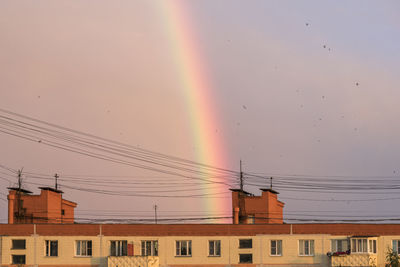 Low angle view of rainbow over buildings against sky