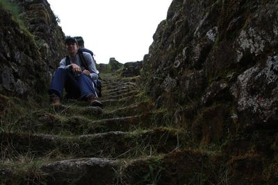 Low angle view of male hiker sitting on old steps