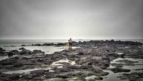 Rear view of man standing on beach against clear sky