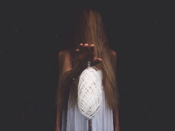 Spooky woman holding white lighting equipment in darkroom