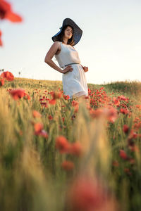 Woman standing on field of poppy-flowers and wheats