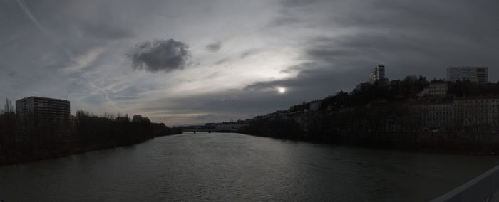 River amidst buildings in city against sky at dusk